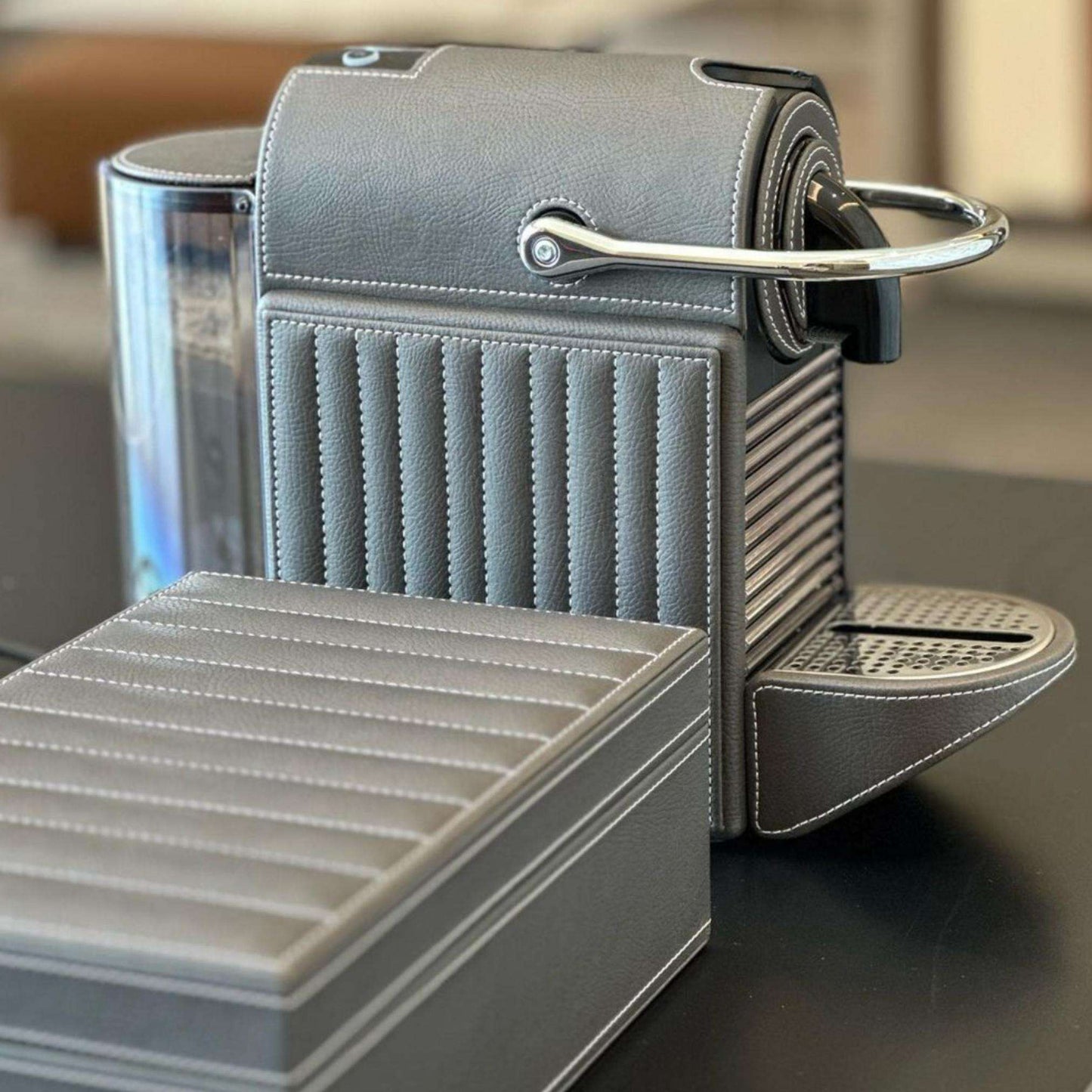 Silver-grey Nespresso Pixie coffee machine covered in leather, styled with a matching storage box