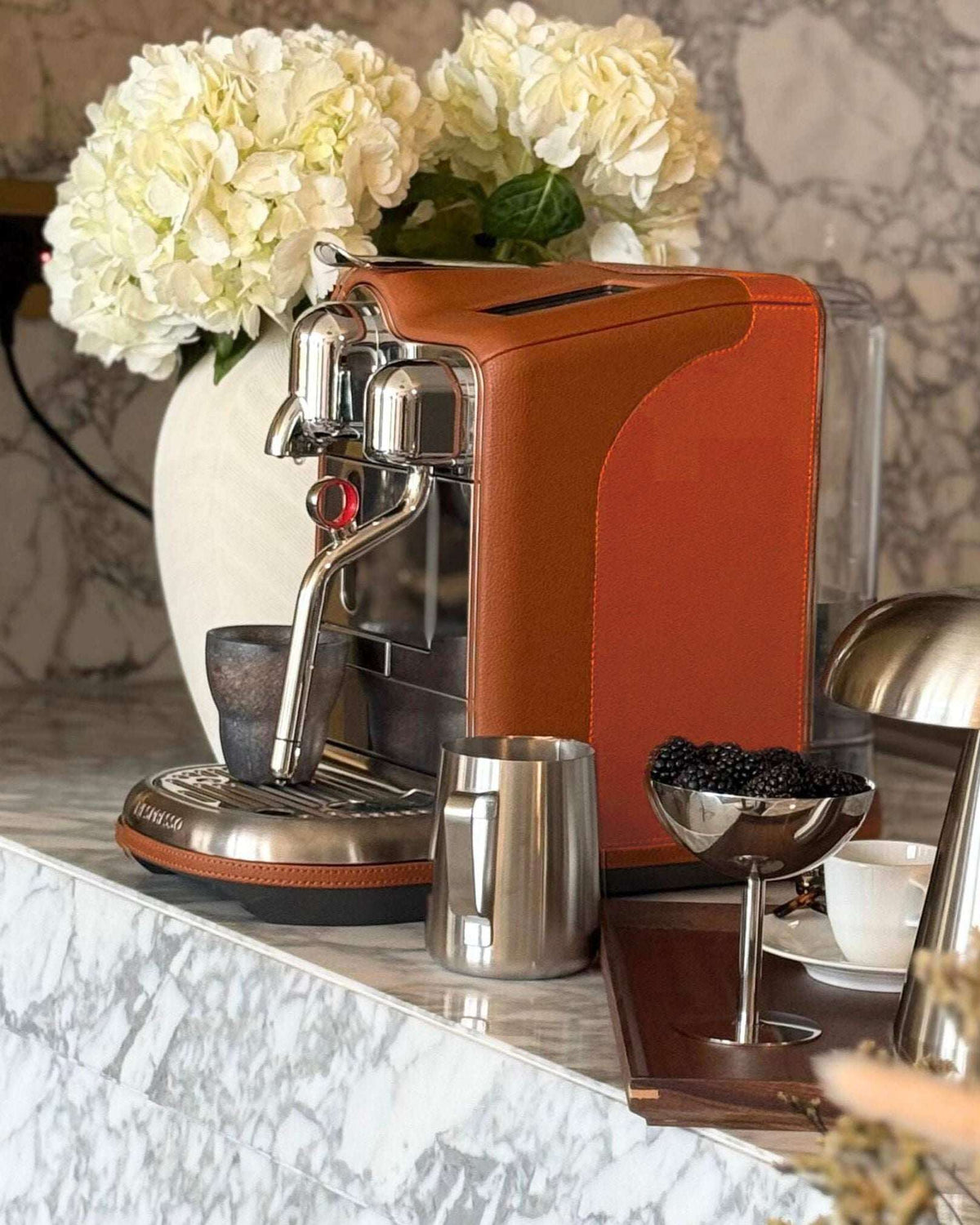 Tan and orange two tone nespresso coffee machine alongside tray with blackberries in a steel cup