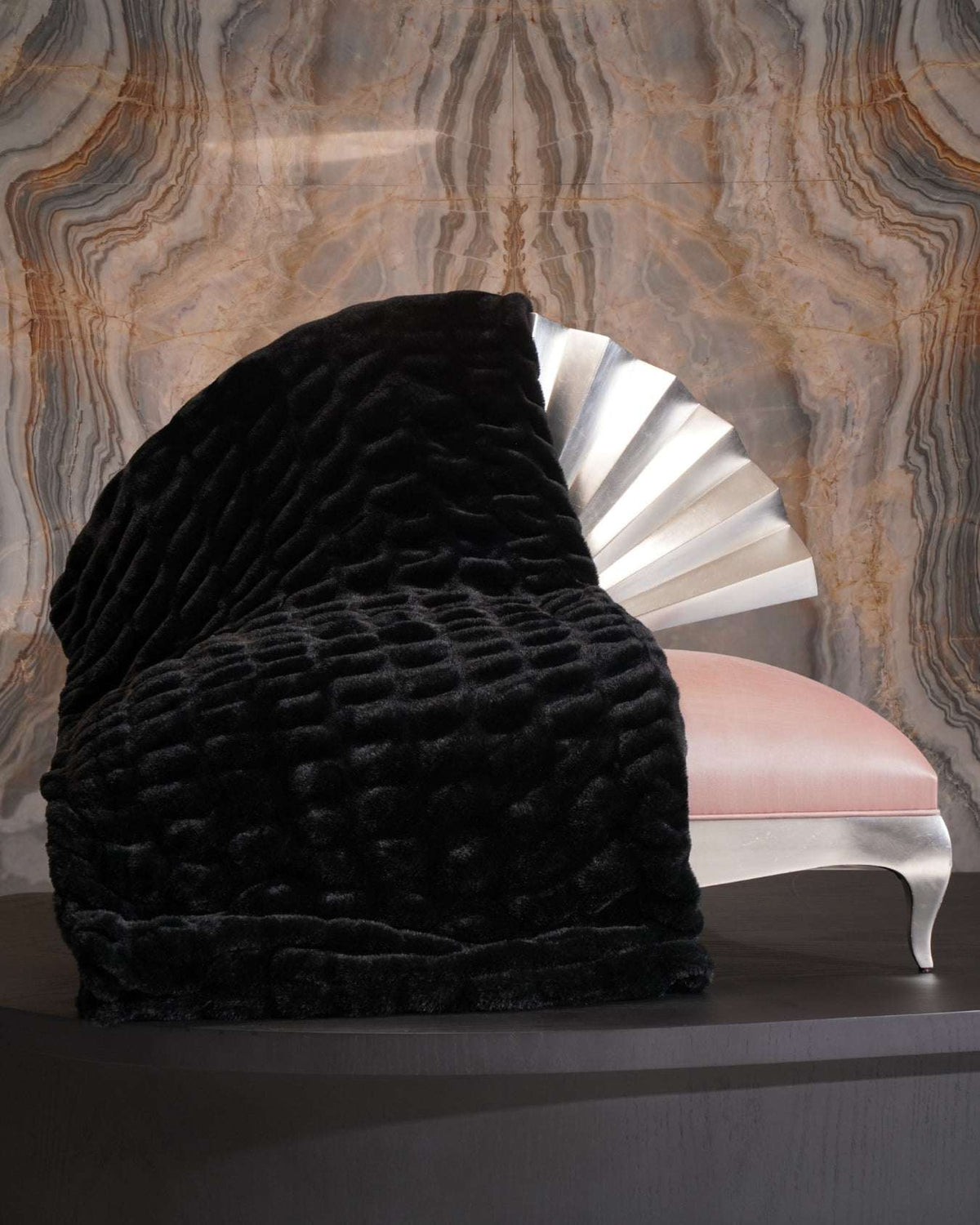 Soft fluffy black throw blanket draped over a decorative sofa bench