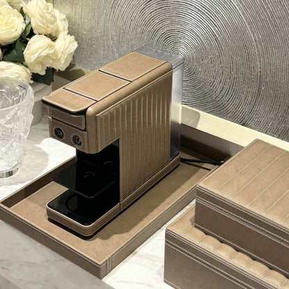 Illy compact coffee capsule machine cladded in a taupe vegan leather made in the UAE. Paired with a tray and storage boxes