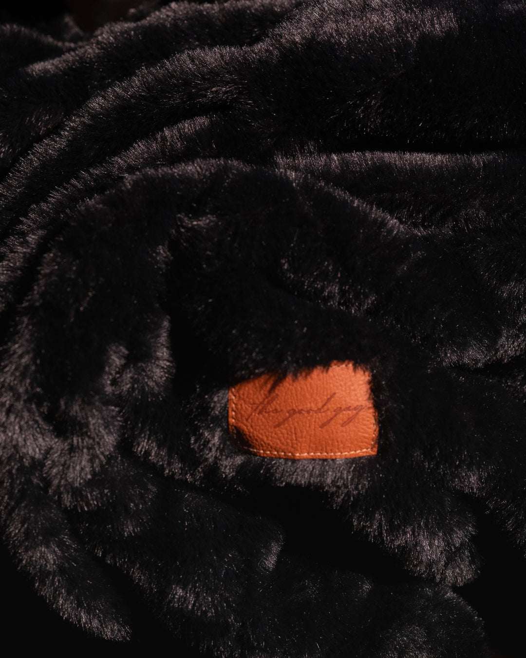 Black throw blanket close up on fluffy soft texture with leatherette tag where you can add personalisation