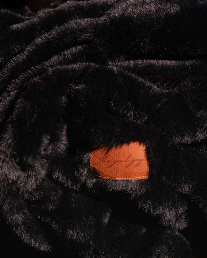 Black throw blanket close up on fluffy soft texture with leatherette tag where you can add personalisation