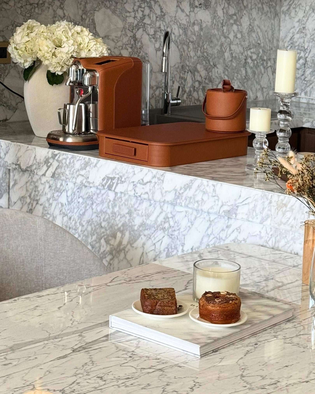 Tan brown creatista pro nespresso coffee machine with matching capsule tray drawer and ice bucket sitting atop a white and grey marble counter
