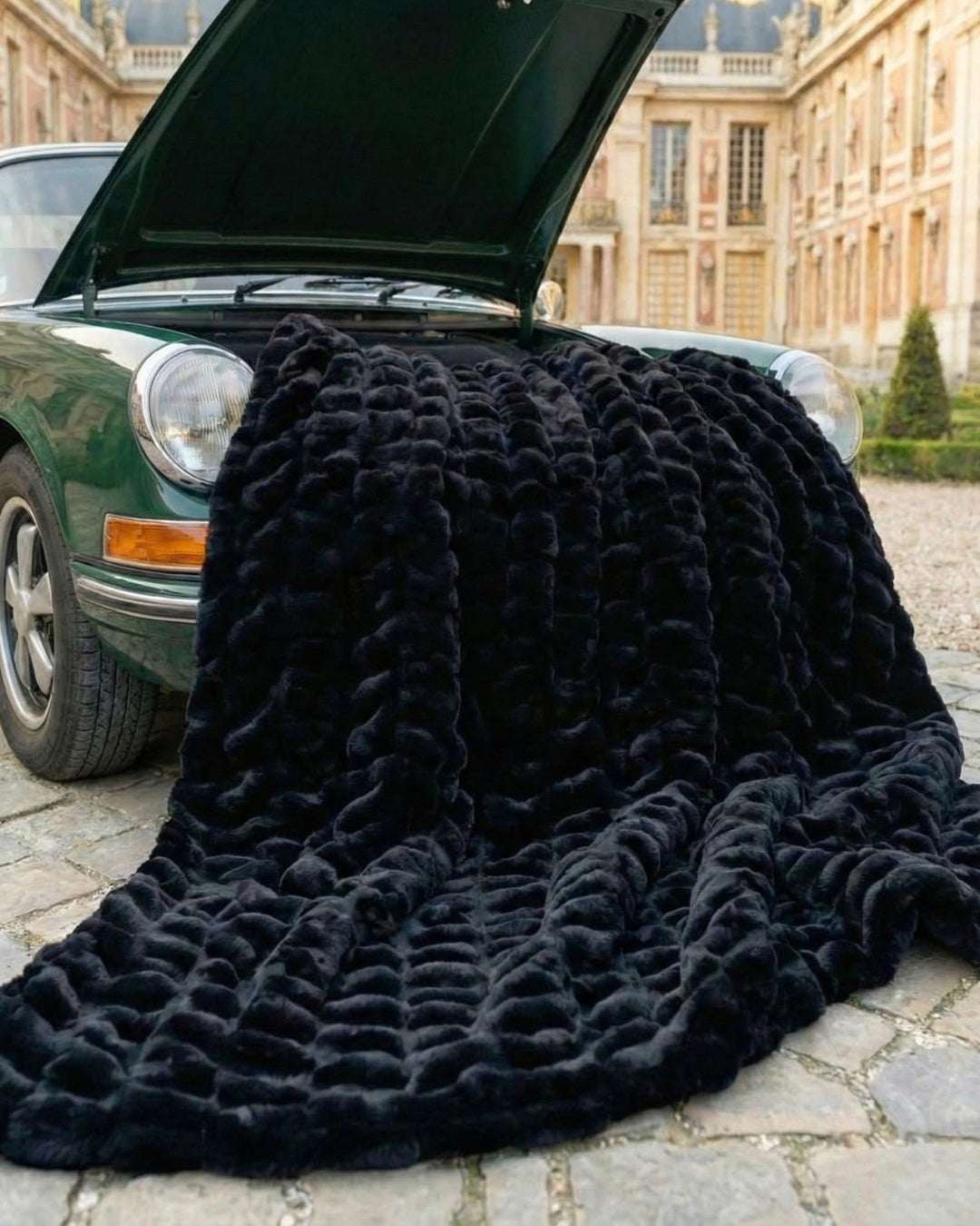 Black throw blanket draped over a vintage green car