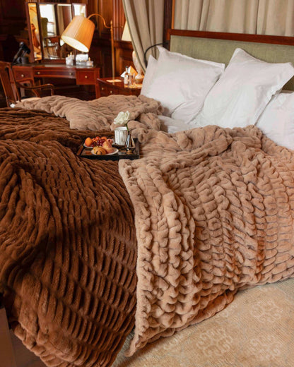 Luxurious bedroom with fluffy brown blankets and a tray of snacks on a bed.