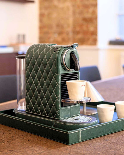 Green luxury leather covered espresso machine on a tray with coffee cups in an office setting.