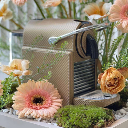 Golden Metallic Nespresso Pixie coffee machine covered in leather, styled as a gift with a floral arrangement