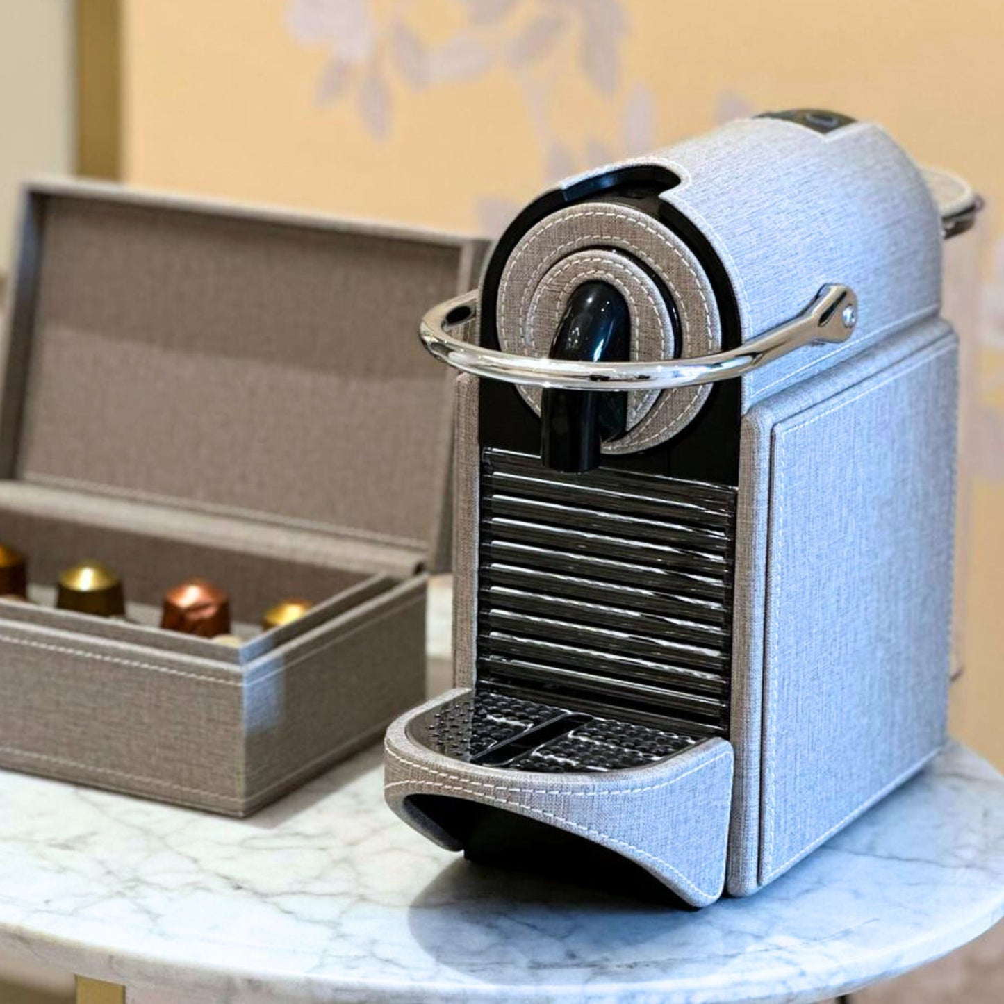 Grey textile like finish Nespresso Pixie coffee machine covered in leather, styled with a matching storage box