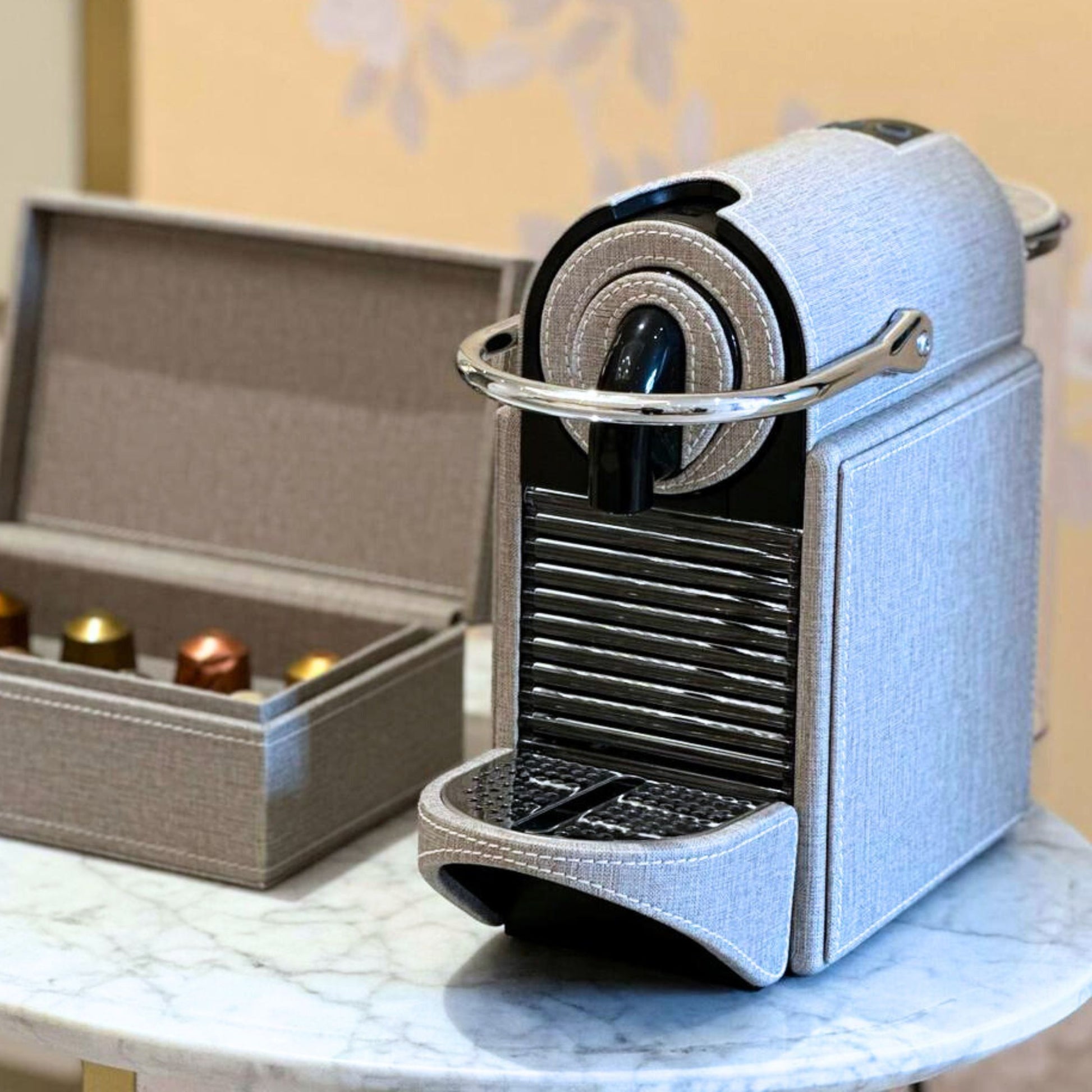 Grey textile like finish Nespresso Pixie coffee machine covered in leather, styled with a matching storage box