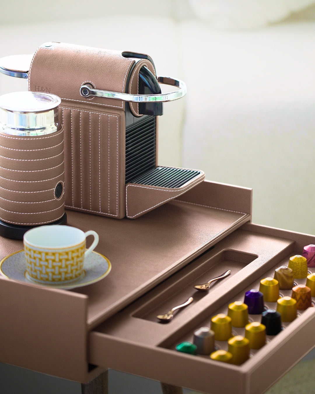 taupe brown leather wrapped luxury Coffee machine set with a drawer containing coffee pods and a cup on a saucer.